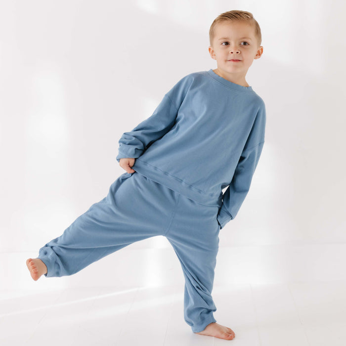Child wearing a blue onesie against a white background