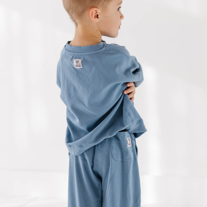 Child wearing a blue outfit with a visible brand logo on a white background