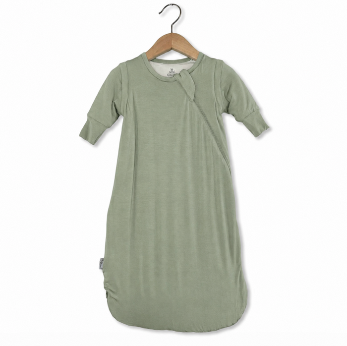 Green baby swaddle on a wooden hanger against a white background