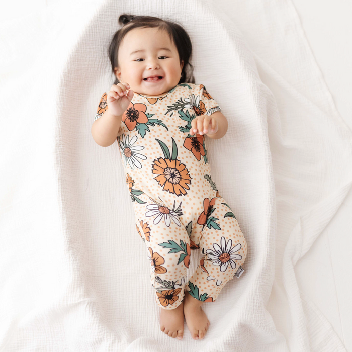Baby wearing a floral onesie on a white blanket