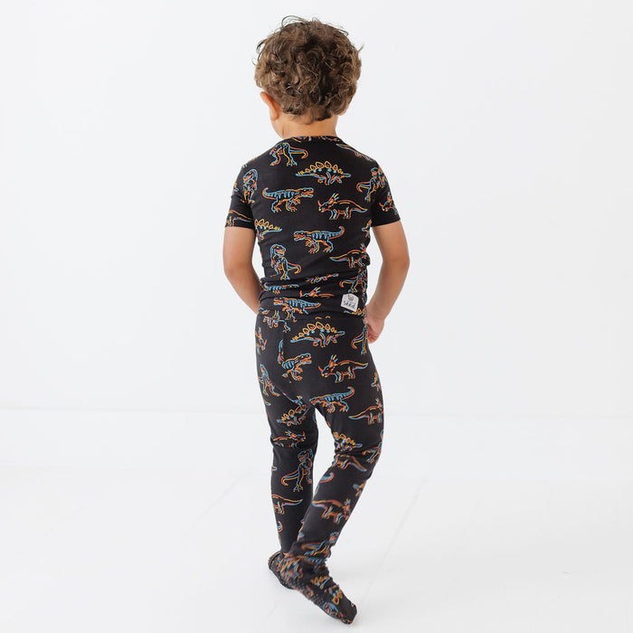 Child wearing a black dinosaur-patterned onesie on a white background
