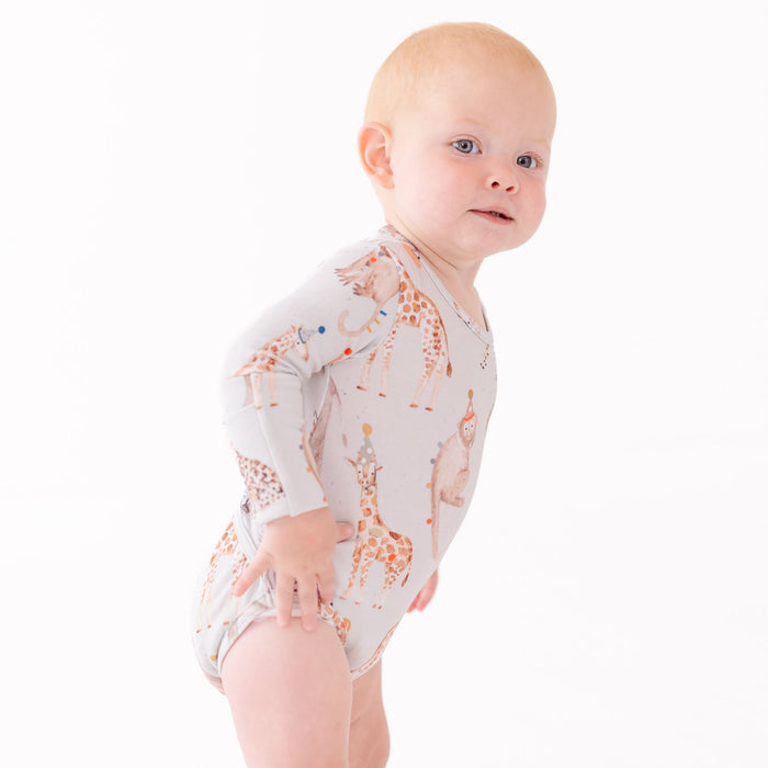 Baby wearing a long-sleeve onesie with giraffe pattern on a white background