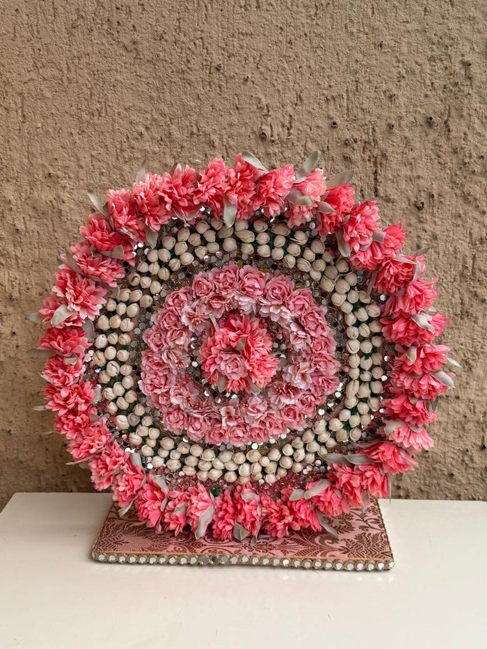 Pink floral circular idol backdrop stand with bead border and scalloped garland, on platform