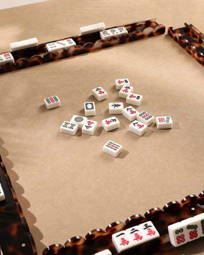 Tortoise shell acrylic mahjong racks framing tiles on felt play surface