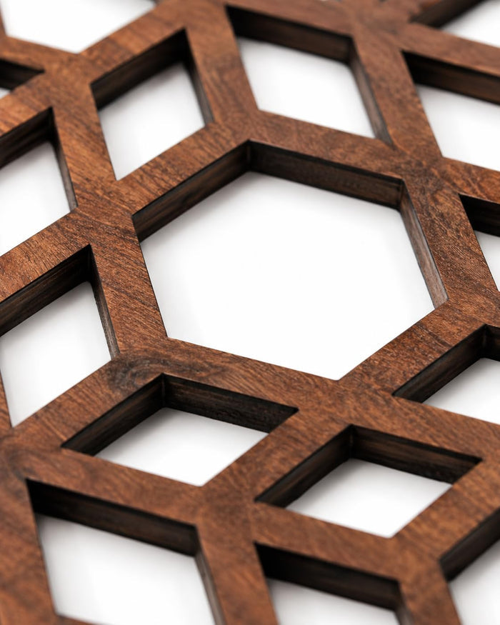 Close-up square dark brown wooden trivet with hex cube lattice cutouts