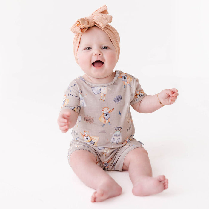 Baby wearing a patterned onesie and headband on a white background